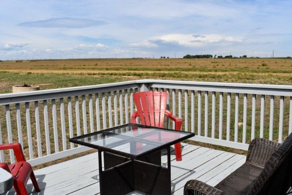 Deck with red chairs and wide-open countryside views